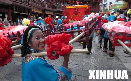 8月8日，在贵州省黔南布依族苗族自治州都匀市石板步行街，一位布依族妇女走在婚俗展的队伍里。     当日是第三届都匀国际摄影博览会开幕的第二天，布依族婚俗展示成为都匀的一道亮丽风景。 