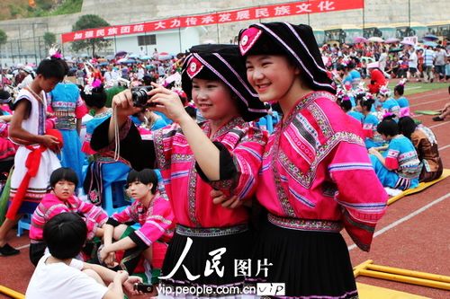 6月22日，2名瑶族少女正在抓拍节庆活动的场面。（郑重声明：凡带有&ldquo;人民图片&rdquo;字样图片，未经许可，不得转载。购图电话010-65368421） 