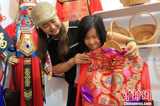 一位重庆的客商正在给小朋友试穿蒙古族民族手工服饰。　年磊 摄